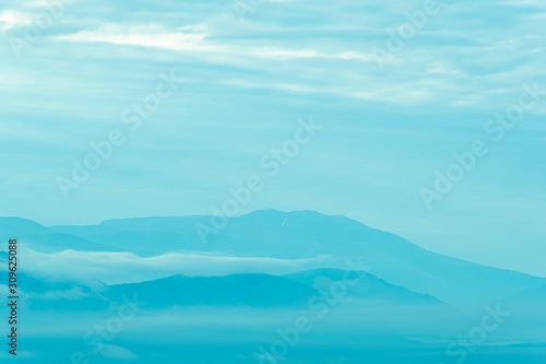 Gentle hills in bluish haze. Soft light in early morning  silhouettes of mountains