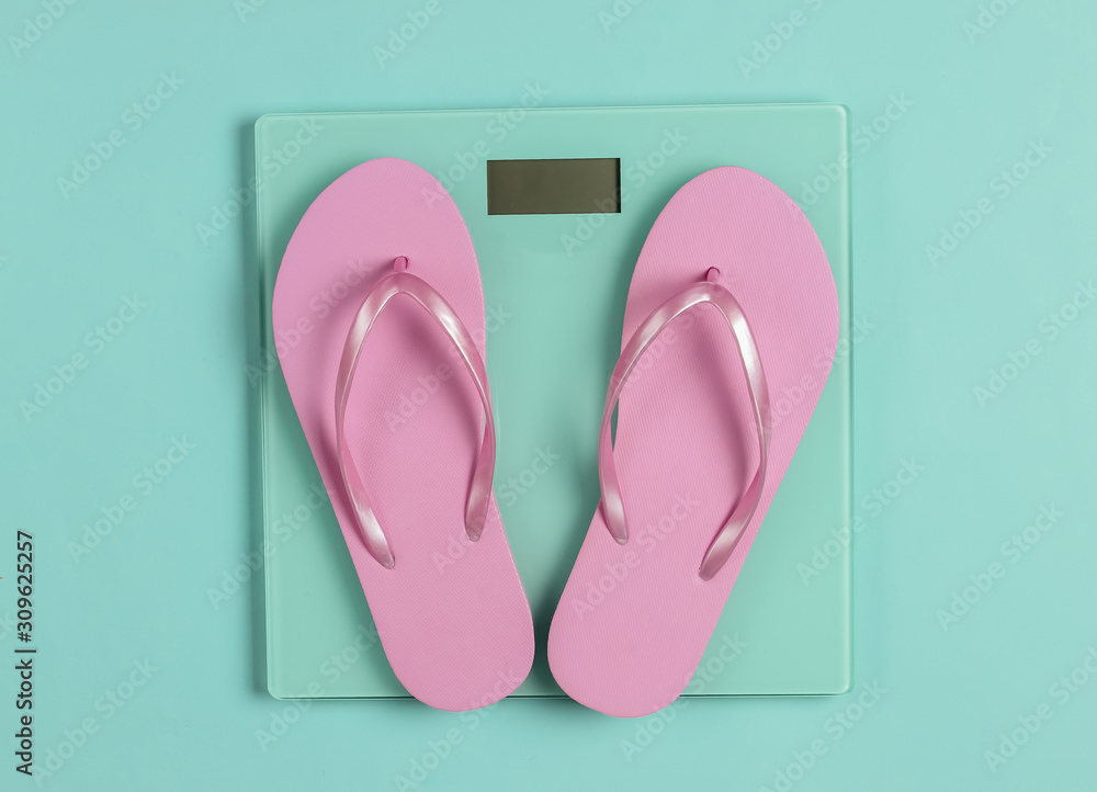 Flip flops on the scales. Studio shot on a blue background. Top view Flip flops on the scales. Studio shot on a blue background. Top view