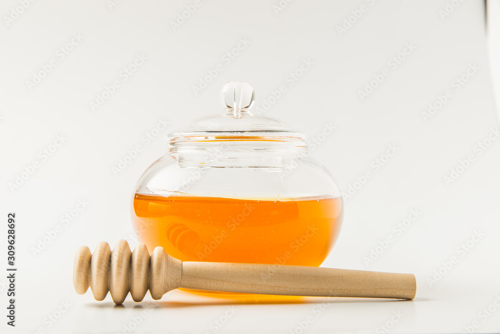 Glass jar of honey with honey dipper isolated on a white background with space for text Glass jar of honey with honey dipper isolated on a white background with space for text