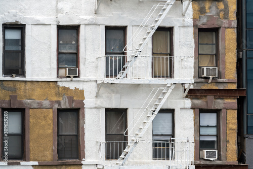 Half-painted New York Building with Fire Escapes. A typical New York City apartment building gets a facelift with some new white paint but the job is only half done..