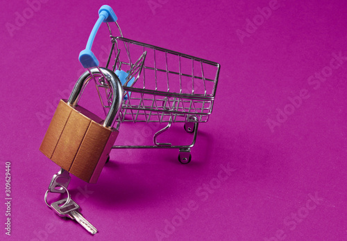 Minimalistic shopping concept. Mini shopping trolley with a lock on pink background.