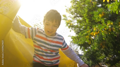 A kid going down a yellow slide in slow motion