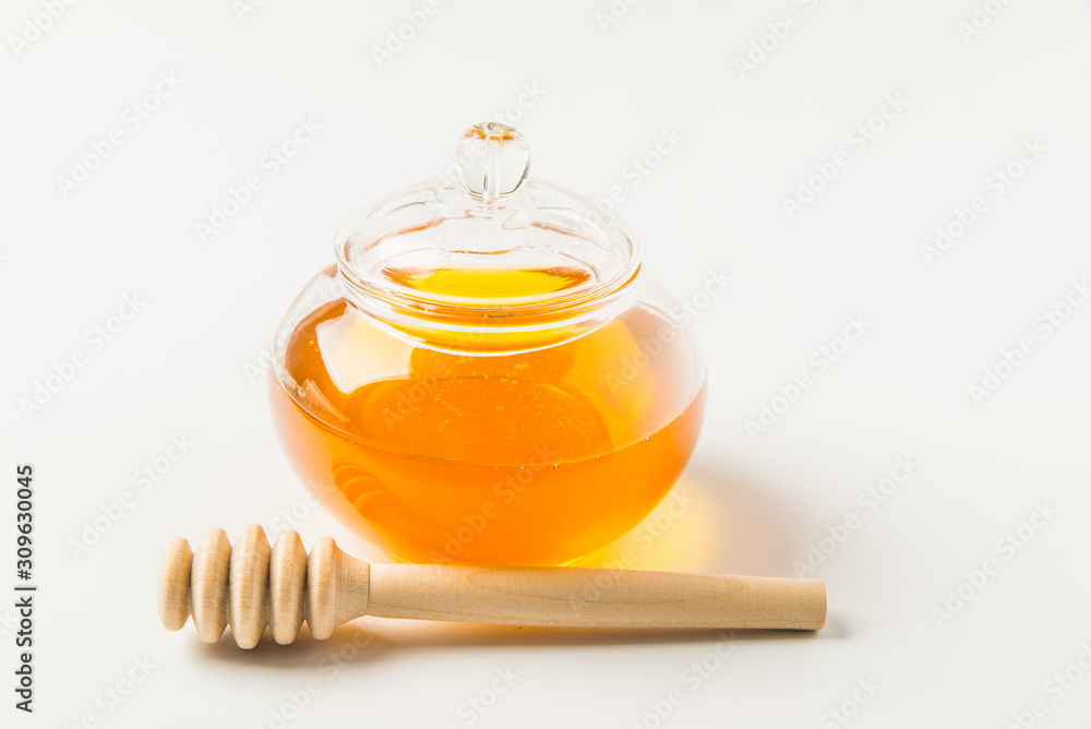 Glass jar of honey with honey dipper isolated on a white background with space for text Glass jar of honey with honey dipper isolated on a white background with space for text