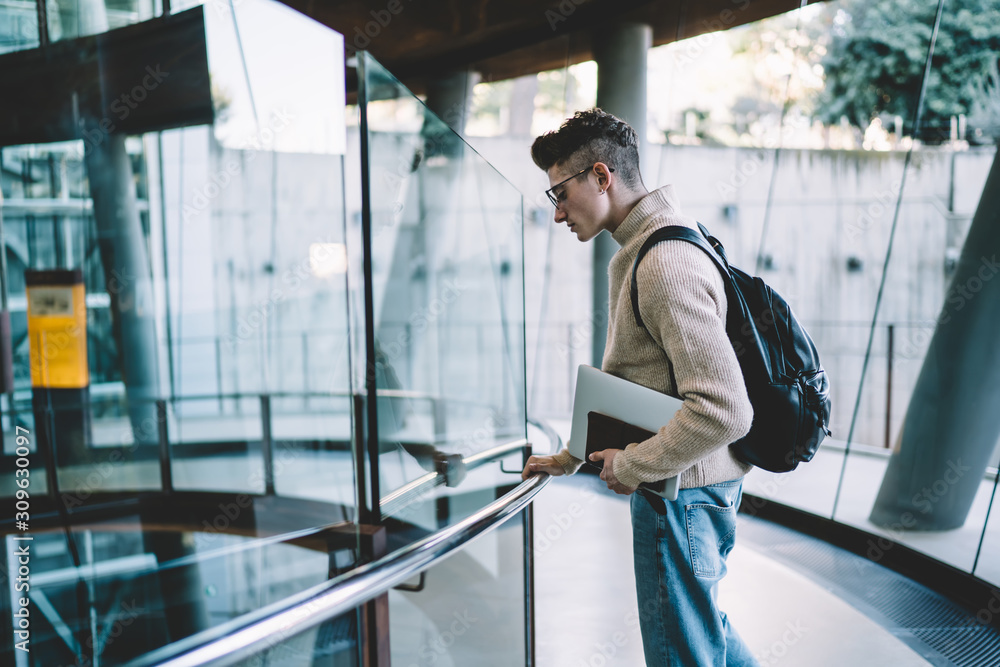 Young man looking down and standing on floor with glass fence