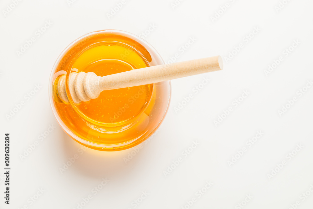 Glass jar of honey with honey dipper isolated on a white background with space for text Glass jar of honey with honey dipper isolated on a white background with space for text