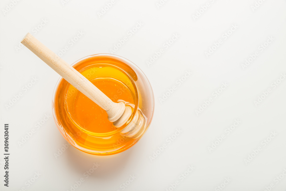 Glass jar of honey with honey dipper isolated on a white background with space for text Glass jar of honey with honey dipper isolated on a white background with space for text