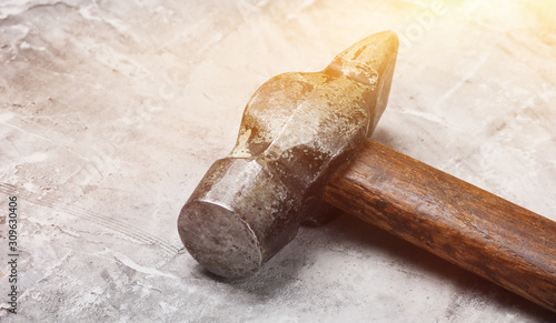 Old hammer on gray concrete background close up