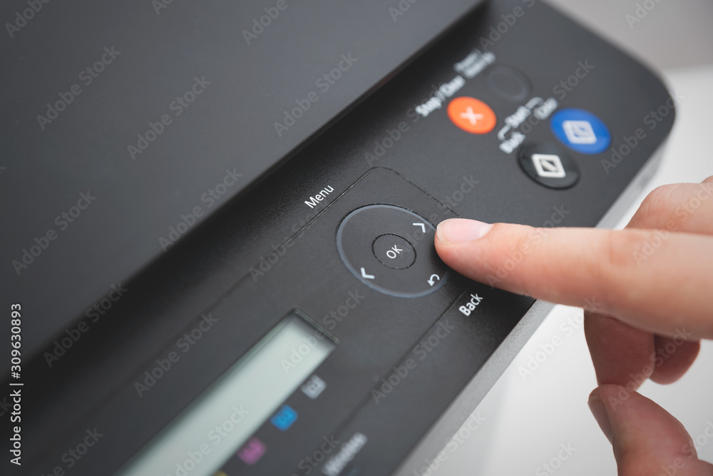 Hand pressing button on panel of printer Hand pressing button on panel of printer