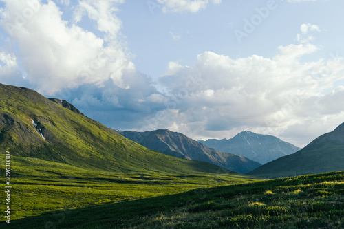 Green hills under blue cloudy sky. Mountain valley for pasture
