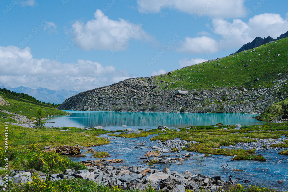 Fototapeta premium Mountain blue lake among rocks. Stone ridge in river valley under clouds. Travel in mountains among hills