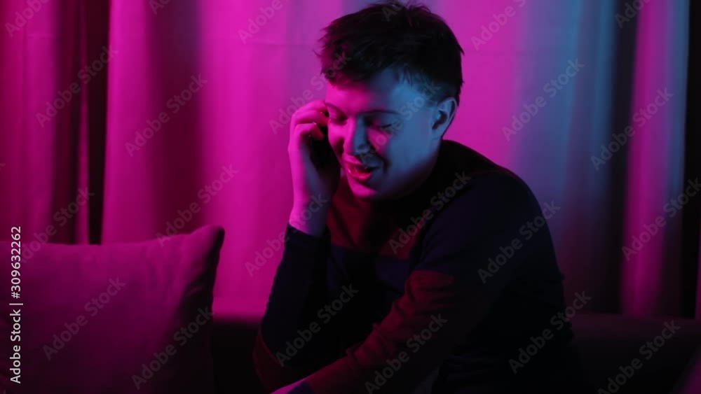 Portrait of funny crazy guy talking on two smartphones with friends indoors. Fun youth conversation. Portrait of funny crazy guy talking on two smartphones with friends indoors. Fun youth conversation.