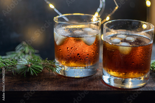 Whiskey in glasses with ice and perspiration on a dark background.