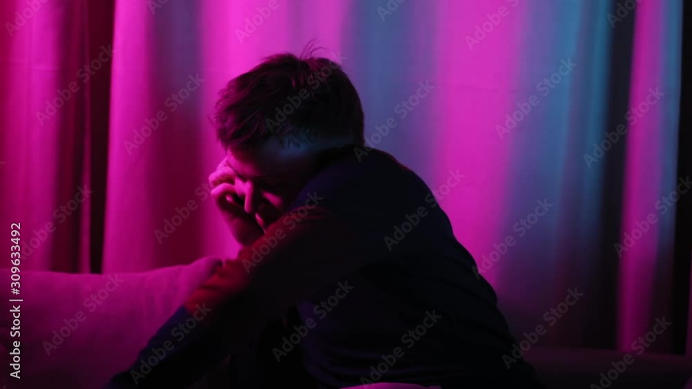 Funny phone conversation with friends. Portrait of excited busy young man talking on different smartphones sitting on the sofa. Funny phone conversation with friends. Portrait of excited busy young man talking on different smartphones sitting on the sofa.