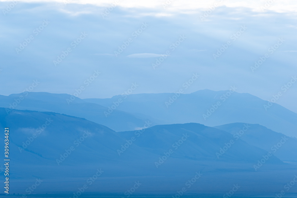 Obraz premium Gentle hills in bluish haze. Soft light in early morning, silhouettes of mountains
