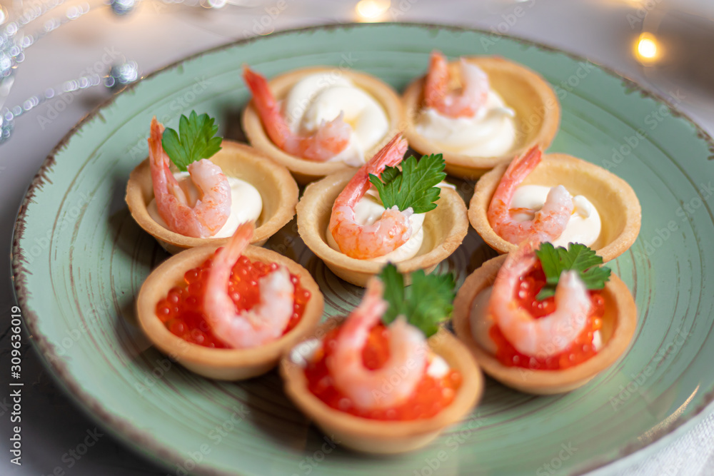 Tartlets with soft cheese, shrimp and red caviar. Holiday dish. On a green plate. Tartlets with soft cheese, shrimp and red caviar. Holiday dish. On a green plate.