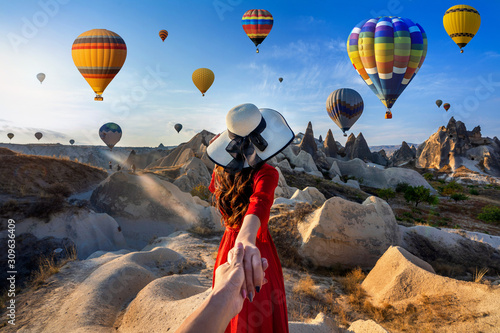 Canvas Print Women tourists holding man's hand and leading him to hot air balloons in Cappadocia, Turkey