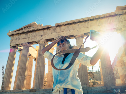 Young woman tourist taking pictures at parthenon in Athens acropolis, Greece