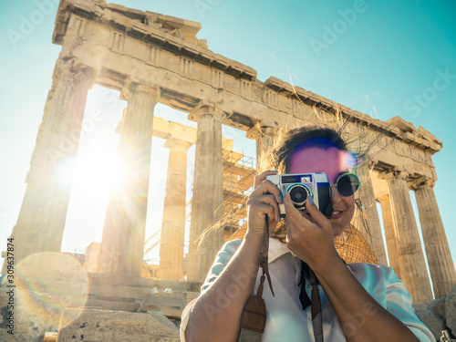 Young woman tourist taking pictures at parthenon in Athens acropolis, Greece
