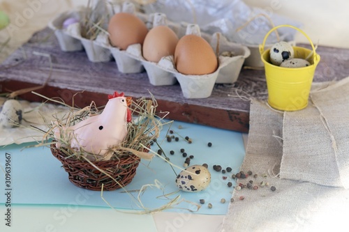 Toy chicken, eggs, hay, Easter decor on a light background