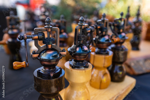 A close up view of traditionally crafted vintage salt and pepper mills, displayed on a market stall during a fair for local traders and artisans.