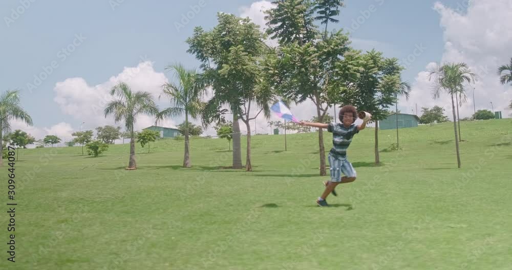 African boy trying to fly a kite in the park. Vacation activity concept. Shot on RED SCARLET-W 5K Camera. 4K. African boy trying to fly a kite in the park. Vacation activity concept. Shot on RED SCARLET-W 5K Camera. 4K.