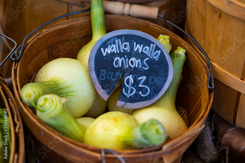 A closeup view of traditional wooden pales filled with walla walla onions, a variety of sweet onion, and a price tag during a local harvest fair photo