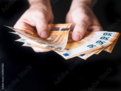 hands of a man holding money isolated on black background, rich and wealth concept 