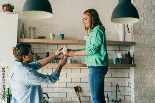 Obraz na plátně Young couple helping each other in kitchen