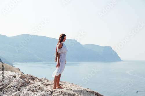 Beautiful woman with long hair in dress on cliff landscape in a journey