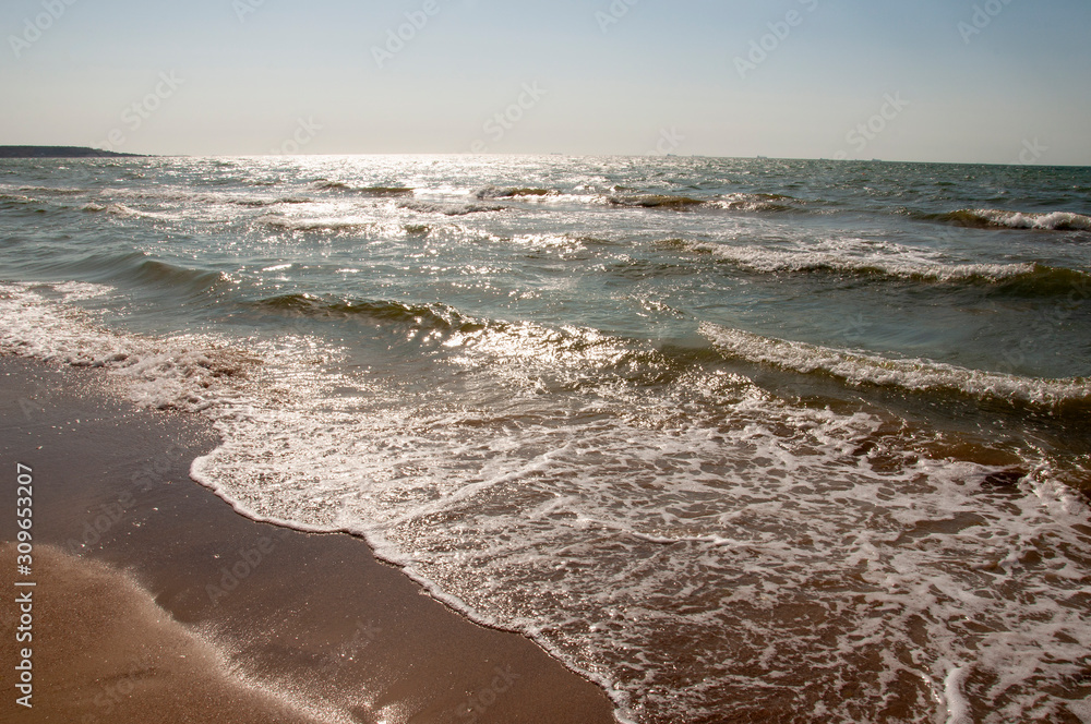Black Sea. Water with waves. Mainly cloudy weather and sun rays. Blue and grey clouds. Before rain. Sand coast