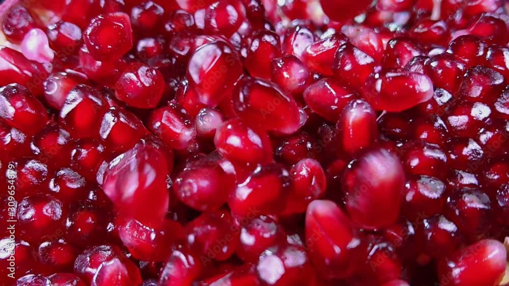 Red pomegranate is falling on a pile of shining juicy grains Red pomegranate is falling on a pile of shining juicy grains