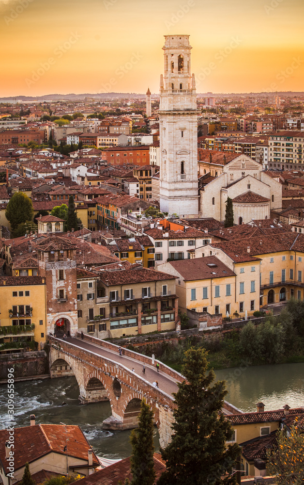 Aerial view of Verona city sunset cityscape, with  Adige river and Complesso della Cattedrale-Duomo , located in Veneto, Italy, viewed from Castel Saint Pietro with yellow sunset sky