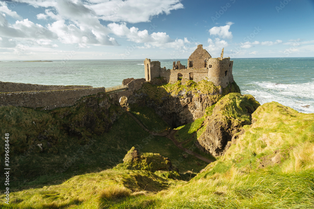 Dunluce Castle, Antrim, Northern Ireland during sunny day with semi cloudy sky.