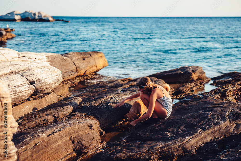 Fototapeta premium Girl and her dog exploring rocky beach
