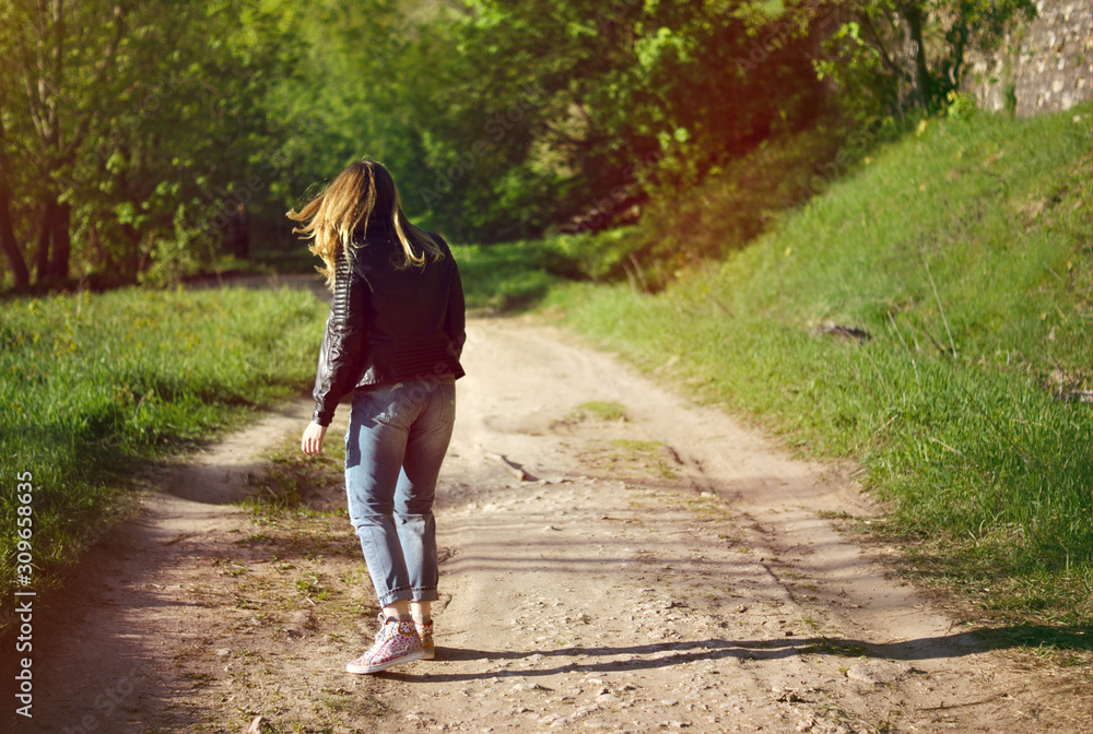 girl walking on the road to the forest looking towards the forest girl walking on the road to the forest looking towards the forest