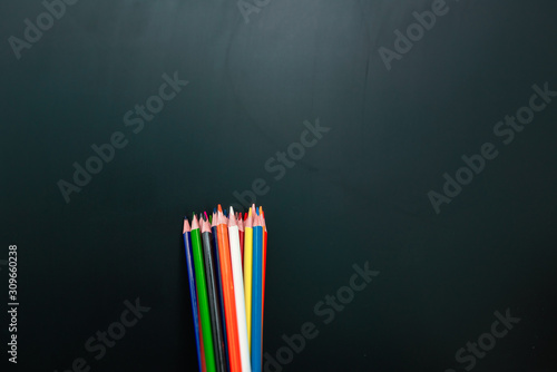 Set of coloured not perfect pencils in front of dark slate photo