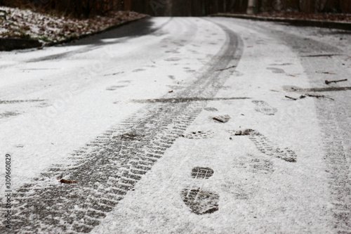 tire tracks and footprints in the first snow on the asphalt