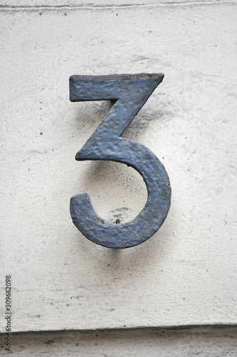 A house number plaque, showing the number three (3)