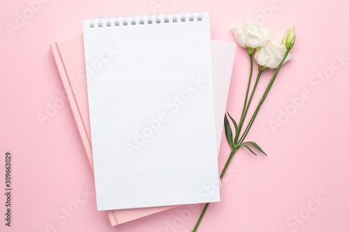Beautiful white eustoma flower and notebook on pink background