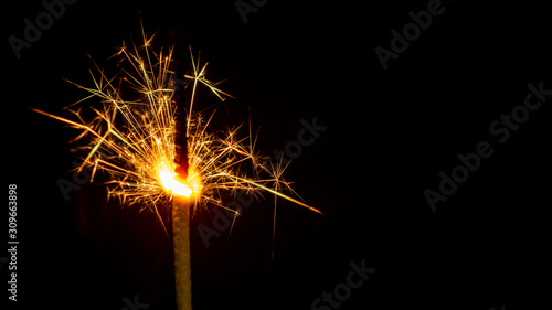 Sparkling sparkler on a black background. New Year theme.