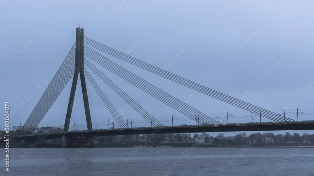Time lapse of slow traffic on suspended bridge. Many vehicles slowly move in congestion at early evening. Hundreds of cars moving on a bridge Time lapse of slow traffic on suspended bridge. Many vehicles slowly move in congestion at early evening. Hundreds of cars moving on a bridge