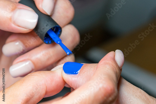 Beautiful manicure process. Nail polish being applied to hand  polish is a blue color. close up