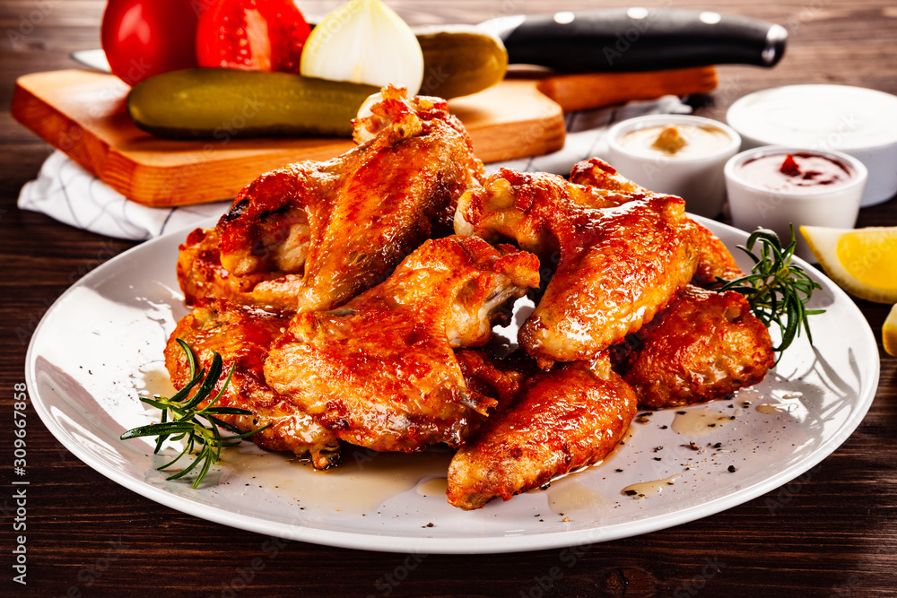 Barbecued chicken wings with french fries and vegetable salad on timber Barbecued chicken wings with french fries and vegetable salad on timber