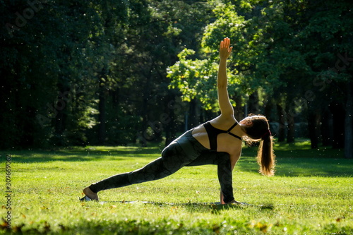 young woman practice yoga asana in sunny summer green park