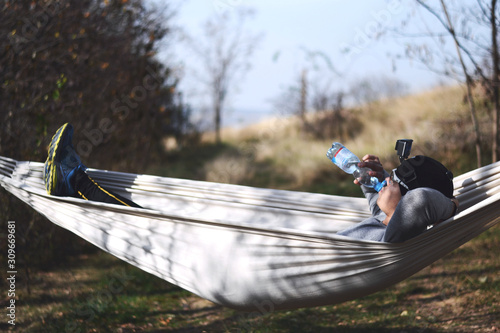 Young happy man relaxing lying in hammock on top of forest