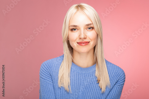 portrait of young smyiling woman in blue on pink bakground