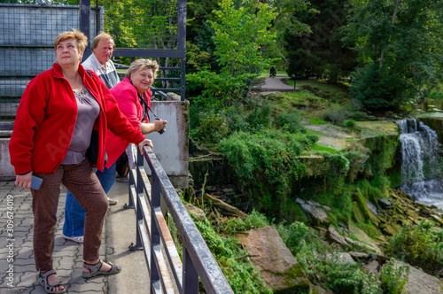 A group of Mature tourists relax and take pictures in the city Park at the waterfall