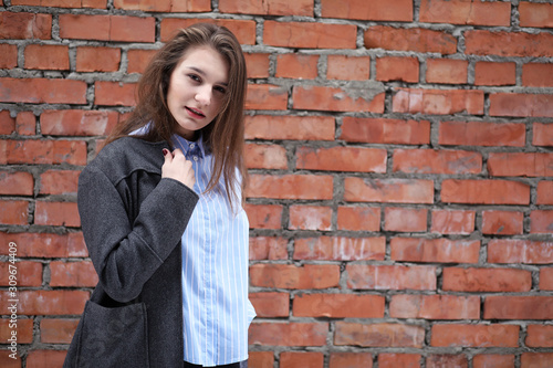 Young beautiful girl near red brick wall posing