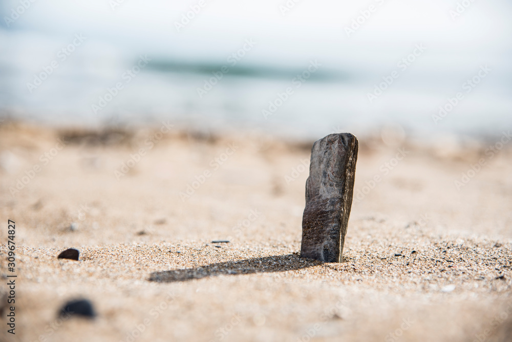 Stone monolith in the sand on the beach Stone monolith in the sand on the beach