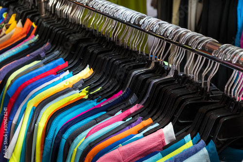 colorful t-shirts hanging on second hand clothing market -